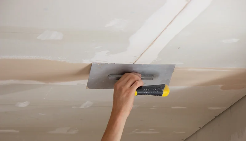 Trowel smoothing compound across a ceiling