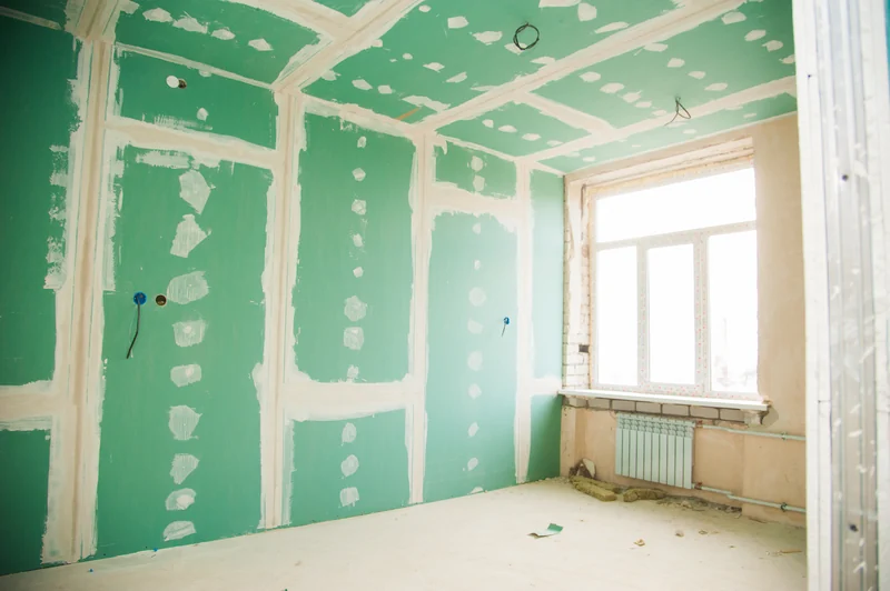 A room lined in green moisture-resistant board, walls and ceiling, with the fastener heads spotted in compound