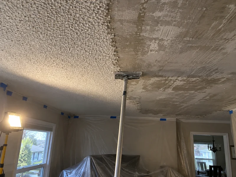 Pole scraper at the boundary between scraped and unscraped popcorn ceiling