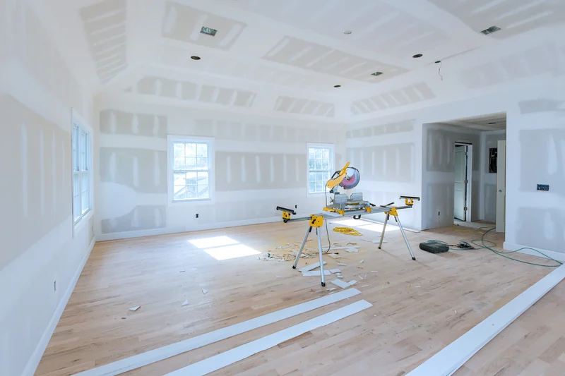 Large unfinished room with a wood floor and a miter saw set up