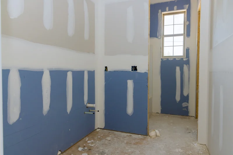 Blue-faced board run around the lower walls of a bathroom remodel with the plumbing stubbed out